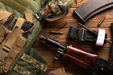 Askeri zırh, miğfer ve mühimmat, Kalaşnikof saldırı tüfeği ve kahverengi ahşap üzerinde ilk yardım turnikesi. Askeri zırh. Düz yat. askeri kavram.