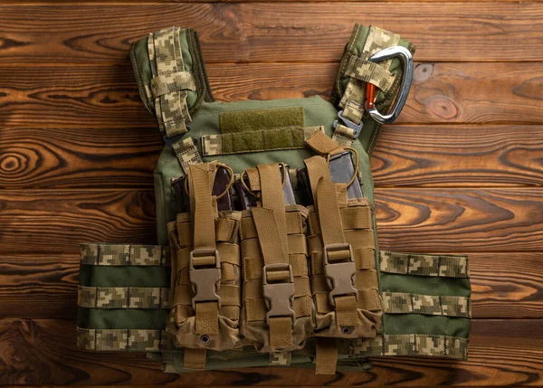 Military body armor with a pouch on a brown textured wood. army body armor. View from above. Place to copy. Military concept.