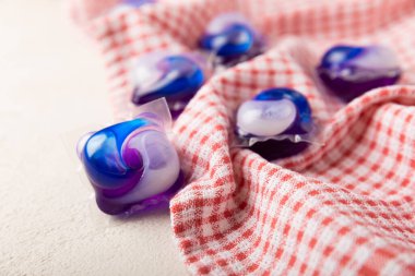 Çamaşır kapsülleri ve mutfak havlusu beyaz mermer arka planda. Çamaşır makinesinde çamaşır yıkamak için deterjan. Saflık kavramı. Metin için yer.