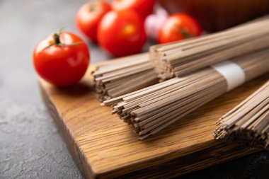 Siyah desenli mermer arka planda kiraz domatesli karabuğday makarnası. Çiğ makarna. Glütensiz yemek için gerekli malzemeler. Sağlıklı yiyecekler. Kopyalanacak yer.