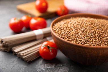 Siyah desenli mermer arka planda karabuğday ezmesi ve kiraz domatesli bir kasede karabuğday. Çiğ karabuğday. Glüten içermeyen mısır gevreği. Sağlıklı yiyecekler. Kopyalanacak yer.