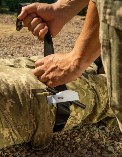 Army medics practice applying a tourniquet to the leg of a wounded soldier. Combat tactical equipment. Combat use Turnstile. The concept of military medicine.