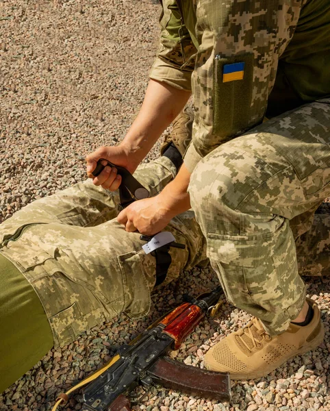 Army medics practice applying a tourniquet to the leg of a wounded soldier. Combat tactical equipment. Combat use Turnstile. The concept of military medicine.