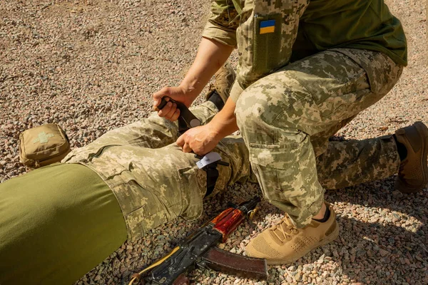 Army medics practice applying a tourniquet to the leg of a wounded soldier. Combat tactical equipment. Combat use Turnstile. The concept of military medicine.