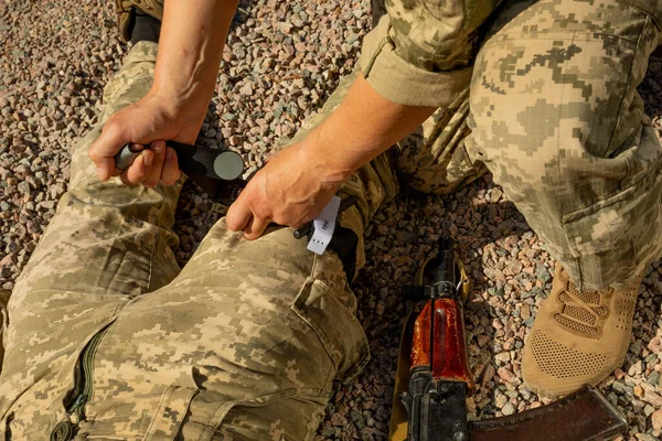 Army medics practice applying a tourniquet to the leg of a wounded soldier. Combat tactical equipment. Combat use Turnstile. The concept of military medicine.