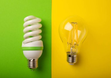 Elektrik ampulleri. Enerji verimliliği kavramı. LED lamba parlak lambaya karşı. Sarı arkaplan üzerindeki kompozisyon. Ekonomik ve çevre dostu ampul kavramını kullan.