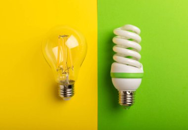 Elektrik ampulleri. Enerji verimliliği kavramı. LED lamba parlak lambaya karşı. Sarı arkaplan üzerindeki kompozisyon. Ekonomik ve çevre dostu ampul kavramını kullan.