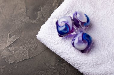 Siyah mermer arka planda çamaşır kapsülleri ve kar beyazı bir havlu. Çamaşır makinesinde çamaşır yıkamak için deterjan. Saflık kavramı. Metin için yer.