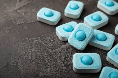 Siyah doku arka planında su yumuşatıcı haplar. Çamaşır makineleri ve bulaşık makineleri için kapsüller, kireçlenme ölçeğini engelliyor. Kopyalanacak yer.