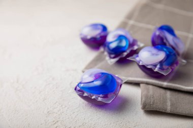 Çamaşır kapsülleri ve mutfak havlusu beyaz mermer arka planda. Çamaşır makinesinde çamaşır yıkamak için deterjan. Saflık kavramı. Metin için yer.