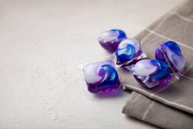 Çamaşır kapsülleri ve mutfak havlusu beyaz mermer arka planda. Çamaşır makinesinde çamaşır yıkamak için deterjan. Saflık kavramı. Metin için yer.