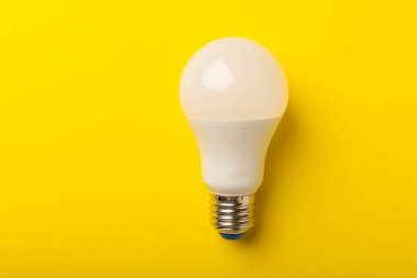 LED lamba enerji verimliliği kavramı. Sarı arka plan bileşimi. Ekonomik ve çevre dostu ampul kavramını kullanın. Eko. Düz katman. Boşluğu kopyala. MOCKUP