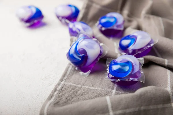 Çamaşır kapsülleri ve mutfak havlusu beyaz mermer arka planda. Çamaşır makinesinde çamaşır yıkamak için deterjan. Saflık kavramı. Metin için yer.