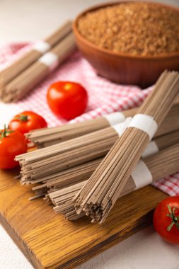 Siyah desenli mermer arka planda kiraz domatesli karabuğday makarnası. Çiğ makarna. Glütensiz yemek için gerekli malzemeler. Sağlıklı yiyecekler. Kopyalanacak yer.
