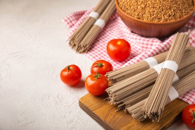 Siyah desenli mermer arka planda kiraz domatesli karabuğday makarnası. Çiğ makarna. Glütensiz yemek için gerekli malzemeler. Sağlıklı yiyecekler. Kopyalanacak yer.