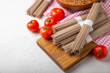 Siyah desenli mermer arka planda kiraz domatesli karabuğday makarnası. Çiğ makarna. Glütensiz yemek için gerekli malzemeler. Sağlıklı yiyecekler. Kopyalanacak yer.