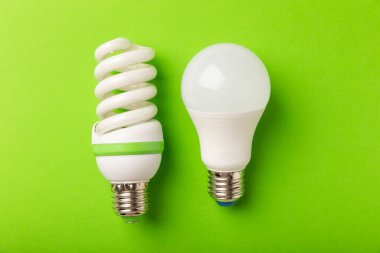 Elektrik ampulleri. Enerji verimliliği kavramı. LED lamba parlak lambaya karşı. Yeşil arka planda kompozisyon. Ekonomik ve çevre dostu bir ampul kavramı kullan.