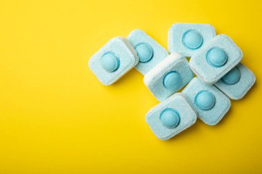 Sarı zemin üzerindeki suyu yumuşatmak için tabletler. Çamaşır makineleri ve bulaşık makineleri için kapsüller, kireçlenme ölçeğini engelliyor. Kopyalanacak yer.