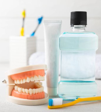 Ağız temizliği ürünleri ve beyaz ahşap arka planda diş modelleri. Diş fırçası, diş macunu ve ağız gargarası beyaz arka planda. Diş sağlığı konsepti. Ağız bakımı konsepti.