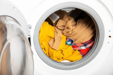  Çamaşır deterjanı kapsülü çamaşır makinesine, yakın çekim. Kapsülde renkli çamaşır jeli. Çamaşır yıkama. Yıkama ve temizlik kavramı.