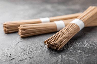 Siyah çimentoyla kaplanmış karabuğday ezmesi. Çiğ erişte. Glütensiz yemek için gerekli malzemeler. Kurutulmuş karabuğday sobalı erişte. Geleneksel Japon yemekleri. Sağlıklı yiyecekler. Kopyalanacak yer.