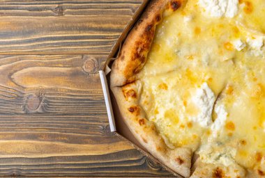 Lezzetli pizza dört peynirli çedar, parmesan peyniri, mozzarella ve kahverengi desenli ahşap ricotta. Pizza arka planı. Yukarıdan görüntüle.