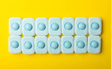 Sarı zemin üzerindeki suyu yumuşatmak için tabletler. Çamaşır makineleri ve bulaşık makineleri için kapsüller, kireçlenme ölçeğini engelliyor. Kopyalanacak yer.