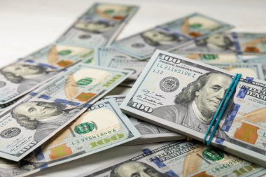Para, beyaz ahşap arka planda 100 dolarlık banknotlar. Para masanın üzerine saçıldı. Finans ve ekonomi kavramları. Para birikimi. Para tasarrufu. Yatırım..