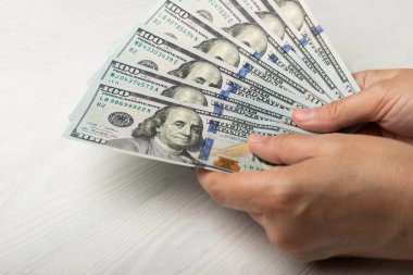 Para elinde. Beyaz dokuya sahip 100 dolarlık banknotlar. Para hesabı. Finans ve ekonomi kavramları. Para biriktirme konsepti. Para biriktiriyorum. Yatırımlar. Boşluğu kopyala.