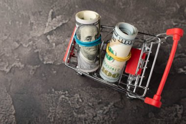 Siyah arka planda dolar banknotları olan bir alışveriş arabası. İş finans alışveriş konsepti. Para tasarrufu. Yatırımlar. Boşluğu kopyala.