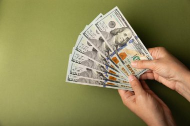 Para elinde. Zeytin arka planında 100 Amerikan doları banknotları. Nakit hesap. Finans ve ekonomi kavramları. Para biriktirme konsepti. Para biriktiriyorum. Yatırımlar. Boşluğu kopyala.