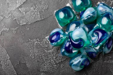 Koyu dokulu arka planda çamaşır kapsülleri. Çamaşır makineleri için sıvı çamaşır tozu içeren kapsüller. Yıkama ve temizlik kavramı. Boşluğu kopyala.