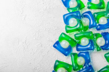 Çamaşır deterjanı yıkamak için kapsüller çamaşır makinesinde çamaşır yıkamak için kapsüller beyaz çimento arka planında. Temizlik kavramı. Çamaşır makinesi için sıvı deterjanlı kapsüller..