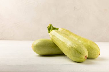 Beyaz ahşap bir masada taze organik kabak. Vejetaryen yemeği. Sağlıklı vejetaryen yemeği. Taze organik ürün. Sebze. Sağlıklı yiyecekler. Boşluğu kopyala.