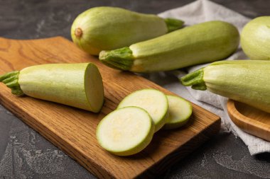 Taze organik kabak ve siyah ahşap bir masada dilimler. Vejetaryen yemeği. Sağlıklı vejetaryen yemeği. Taze organik ürün. Sebze. Sağlıklı yiyecekler. Boşluğu kopyala.