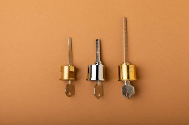 Kahverengi arka planda yeni bir kapı kilidi. Patent ve anahtarlar ön kapıdan. Silindir kilidinin iç mekanizması ve bir takım anahtarlarla temas kurun. Emlak kavramı
