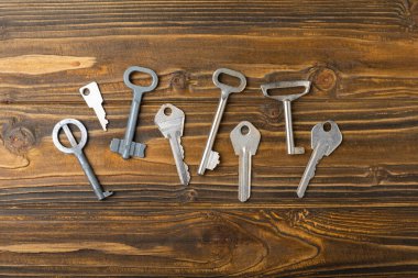 Evin anahtarları. Kahverengi desenli ahşap üzerine kompozisyon. Tasarım elemanı. Gayrimenkul ve sigorta konsepti. Boşluğu kopyala.