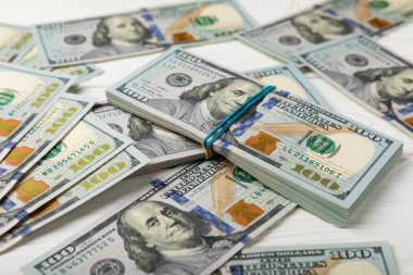 Para, beyaz ahşap arka planda 100 dolarlık banknotlar. Para masanın üzerine saçıldı. Finans ve ekonomi kavramları. Para birikimi. Para tasarrufu. Yatırım..