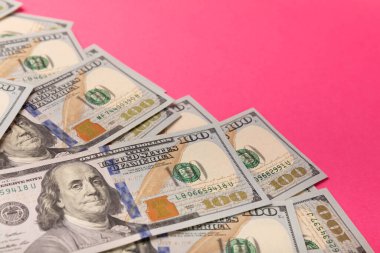 Para, pembe arka planda 100 dolarlık banknotlar. Para masanın üzerine saçıldı. Finans ve ekonomi kavramları. Para tasarrufu konsepti. Para birikimleri. Yatırımlar. telif hakkı.