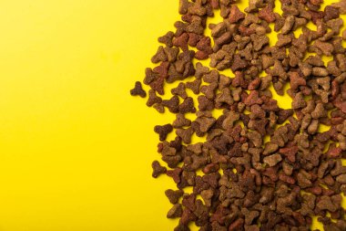 Sarı arka planda kuru kedi maması. Evcil hayvanlarda iyi sağlık ve enerji için vitamin ve besin maddeleri. Boşluğu kopyala.