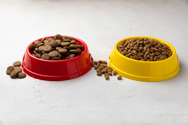 Dry food for cats and dogs in a yellow and red bowl on  cement background.Vitamins and nutrients for good health and pet energy.