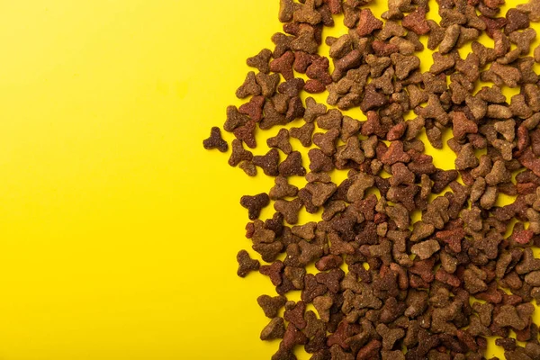Sarı arka planda kuru kedi maması. Evcil hayvanlarda iyi sağlık ve enerji için vitamin ve besin maddeleri. Boşluğu kopyala.