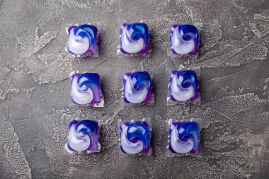 Koyu dokulu arka planda çamaşır kapsülleri. Çamaşır makineleri için sıvı çamaşır tozu içeren kapsüller. Yıkama ve temizlik kavramı. Boşluğu kopyala.