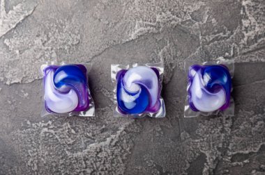 Koyu dokulu arka planda çamaşır kapsülleri. Çamaşır makineleri için sıvı çamaşır tozu içeren kapsüller. Yıkama ve temizlik kavramı. Boşluğu kopyala.