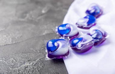 Siyah mermer arka planda çamaşır kapsülleri ve kar beyazı bir havlu. Çamaşır makinesinde çamaşır yıkamak için deterjan. Saflık kavramı. Metin için yer.