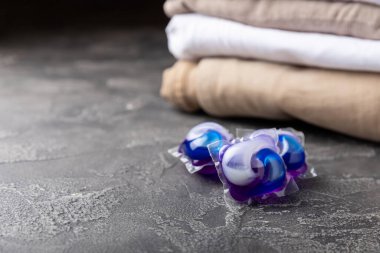 Koyu dokulu arka planda çamaşır kapsülleri. Çamaşır makineleri için sıvı çamaşır tozu içeren kapsüller. Yıkama ve temizlik kavramı. Boşluğu kopyala.