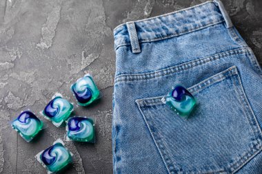 Siyah mermer arka planda mavi kotlu çamaşır kapsülleri. Çamaşır makinesinde çamaşır yıkamak için deterjan. Saflık kavramı. Metin için yer.