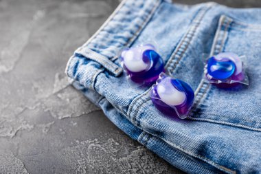 Siyah mermer arka planda mavi kotlu çamaşır kapsülleri. Çamaşır makinesinde çamaşır yıkamak için deterjan. Saflık kavramı. Metin için yer.