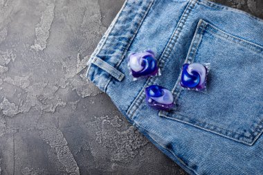 Siyah mermer arka planda mavi kotlu çamaşır kapsülleri. Çamaşır makinesinde çamaşır yıkamak için deterjan. Saflık kavramı. Metin için yer.