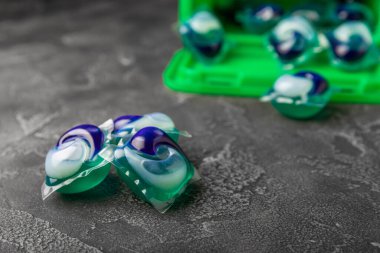 Siyah mermer arka planda çamaşır kapsülleri. Çamaşır makinesinde çamaşır yıkamak için ambalaj tozu. Saflık kavramı. Metin için yer.